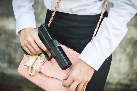 Young woman self defence putting gun in her small handbag, female hide gun in his chest, self-defense criminal concept