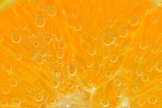 Slice of orange fruit in sparkling water. Orange fruit slice covered by bubbles in carbonated water. Orange fruit slice in water with bubbles. Close-up, macro horizontal image