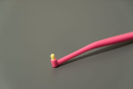 Plastic toothbrush on grey background. Yellow and pink color brush. Healthcare, hygiene for teeth.