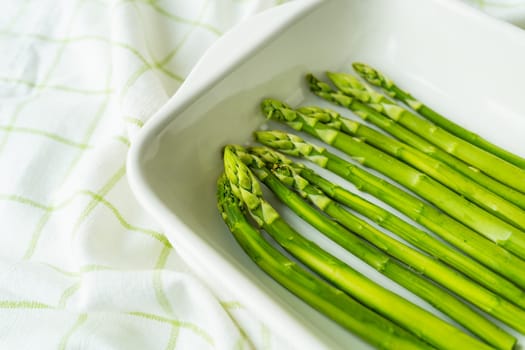 Green asparagus lies in a baking dish in the oven. Clean and wholesome food for health. Seasonal product. Healthy food concept