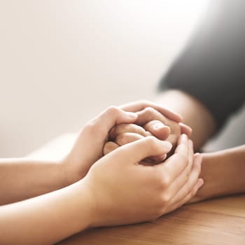 Cropped shot of two people holding hands in comfort.
