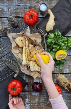 A woman's hand pours lemon juice on freshly cooked squid. Grilled squid. Mediterranean cuisine. Asian cuisine.