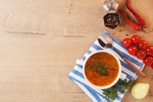 Vegetable soup with potatoes, cabbage, carrots and onions in a white bowl on the kitchen table. Vegetarian food. Copy space