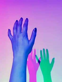 two shadows green and pink from a woman's hand illuminated with blue light.