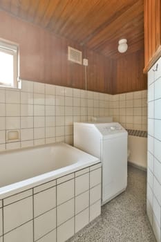 a bathroom with white tiles on the walls and wood paneling around the tub, sink, and dryer