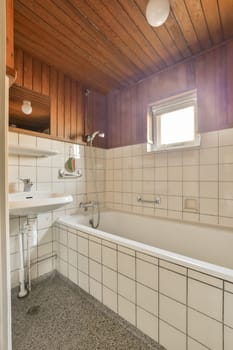 a bathroom with white tiles on the walls and wood paneled ceiling above it, there is a sink in the room