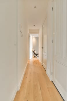 a long hallway with white walls and wood flooring on either side by side, leading to the front door