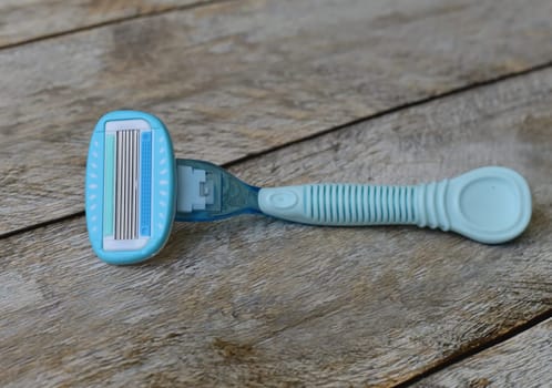 Women's blue razor lies on a wooden background