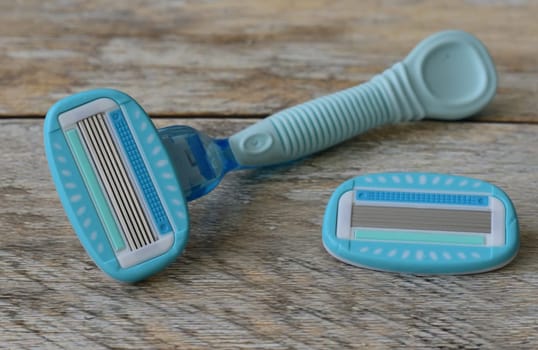 Women's blue razor lies on a wooden background