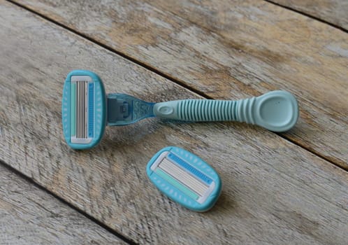 Women's blue razor lies on a wooden background