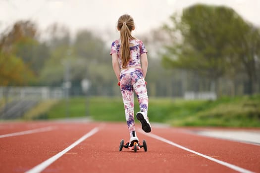 Little girl with scooter on a stadium