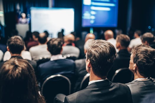 Speaker giving a talk in conference hall at business event. Rear view of unrecognizable people in audience at the conference hall. Business and entrepreneurship concept