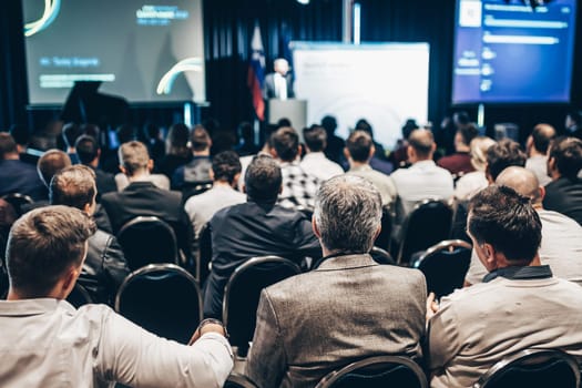 Speaker giving a talk in conference hall at business event. Rear view of unrecognizable people in audience at the conference hall. Business and entrepreneurship concept