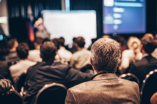 Speaker giving a talk in conference hall at business event. Rear view of unrecognizable people in audience at the conference hall. Business and entrepreneurship concept