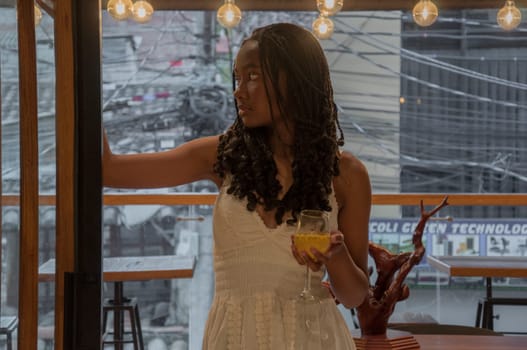 young attractive afro woman at a party standing with a glass of alcochol in an elegant dress. High quality photo