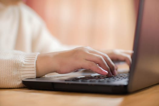 Woman sitting at desk and working on laptop in office at home close-up. Close up of woman hand using laptop sitting in office and doing research.