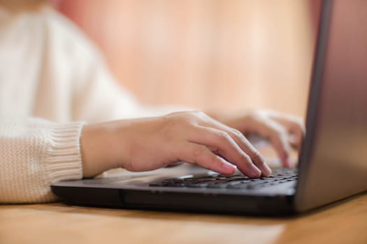 Woman sitting at desk and working on laptop in office at home close-up. Close up of woman hand using laptop sitting in office and doing research.