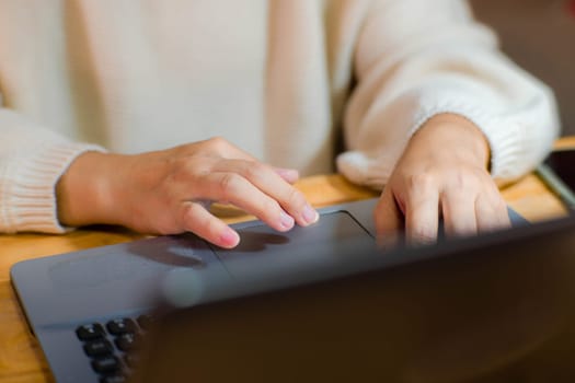 Woman sitting at desk and working on laptop in office at home close-up. Close up of woman hand using laptop sitting in office and doing research.