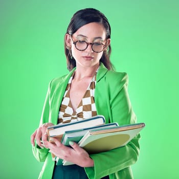 Woman, teacher and books with reading in studio, green background with thinking for career vision. Young model, education and ideas with glasses, mockup and with fashion, ideas and focus.