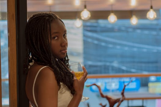 afro teenager girl with depressed face at a party with a cocktail in her hand. High quality photo