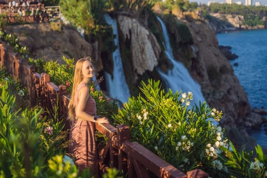 Beautiful woman with long hair on the background of Duden waterfall in Antalya. Famous places of Turkey. Lower Duden Falls drop off a rocky cliff falling from about 40 m into the Mediterranean Sea in amazing water clouds. Tourism and travel destination photo in Antalya, Turkey. Turkiye.