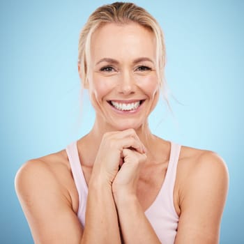 Woman, beauty and face with teeth in portrait, dental and skincare with veneers, oral care and wellness on blue background. Health, hands and smile, natural cosmetics with facial and orthodontics.