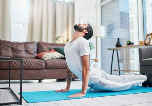 Yoga is for everyone and anyone. a handsome young man practising yoga in his living room at home