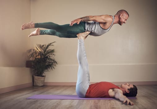 Working those legs. Full length shot of a handsome young man doing acro yoga with his partner in a yoga studio