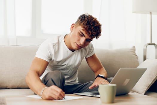 man typing t-shirt student education male home call cup browsing couch sofa white phone wireless business cyberspace room
