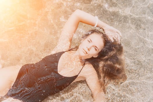 Woman travel sea. Young Happy woman in a long red dress posing on a beach near the sea on background of volcanic rocks, like in Iceland, sharing travel adventure journey