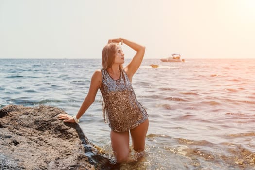 Woman travel sea. Young Happy woman in a long red dress posing on a beach near the sea on background of volcanic rocks, like in Iceland, sharing travel adventure journey