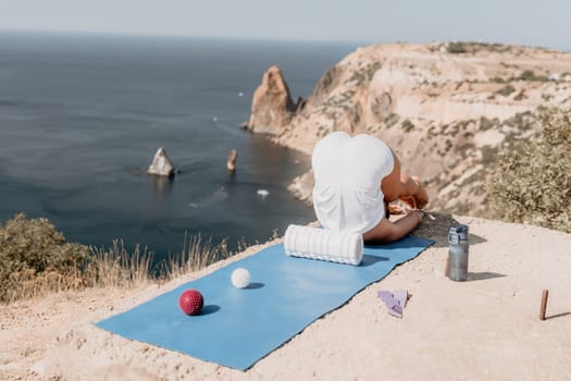 Middle aged well looking woman with black hair doing Pilates with the ring on the yoga mat near the sea on the pebble beach. Female fitness yoga concept. Healthy lifestyle, harmony and meditation.