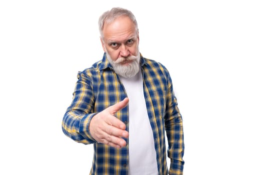 charming well-groomed senior pensioner a gray-haired man with a beard in a shirt extends his hand to greet.