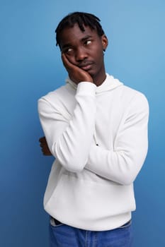 thinking model dark-skinned young brunette man looks away in a white sweater.