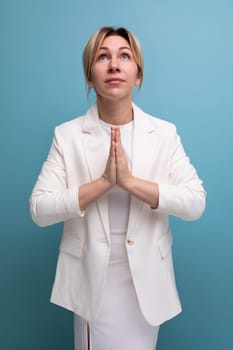 young slender female adult wearing jacket and dress praying.