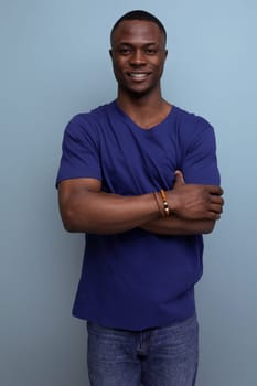 pleasant well-groomed cute young african man in a blue t-shirt on a blue background.