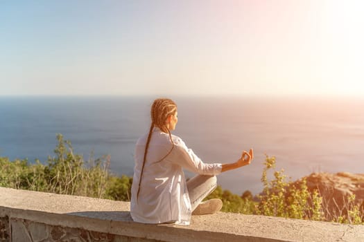 Yoga woman mountains. Profile of a woman doing yoga in the top of a cliff in the mountain. Woman meditates in yoga asana Padmasana.