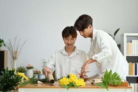 Cheerful gay couple arranging flowers, spending good time together at home. LGBT, love and lifestyle relationship concept.