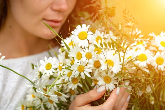 A middle-aged woman holds a large bouquet of daisies in her hands. Wildflowers for congratulations.