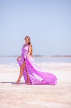 Woman pink salt lake. Against the backdrop of a pink salt lake, a woman in a long pink dress takes a leisurely stroll along the white, salty shore, capturing a wanderlust moment