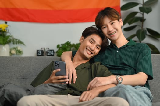 Beautiful image of gay couple embracing, relaxing on couch at home. LGBT, love and human rights concept.