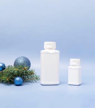 Merry Christmas pharmacy white bottles of pills, tablets, drugs, Christmas tree, sparkling toy balls on blue background. Winter holidays, New Year medical concept. Vertical plane