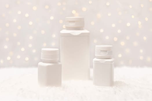 Christmas pharmacy white bottles,containers of pills, tablets,drugs in snow with Christmas,New Year lightening bokeh on background. Winter holidays, medical concept. Copy space,horizontal plane