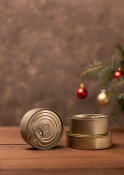 Christmas canned food, products, preservation, packed fish, meat, vegetables in can on wooden table Christmas tree and toy balls. Copy space. New Year food concept. Vertical plane, space for text