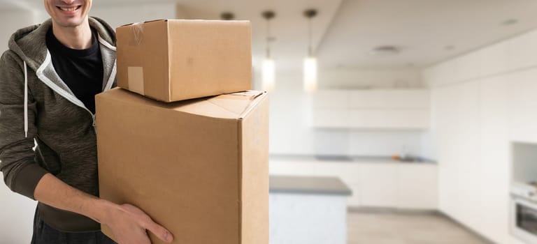 young man carries moving boxes.