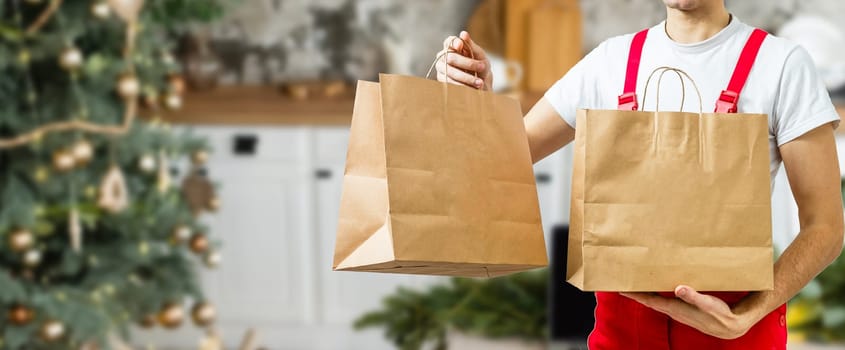 Young handsome delivery man holding paper bag with takeaway food happy with big smile