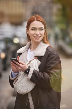 happy woman communicates with friends via video link outdoors on an old town street.