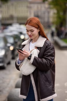 happy woman communicates with friends via video link outdoors on an old town street.