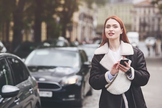 happy woman communicates with friends via video link outdoors on an old town street.