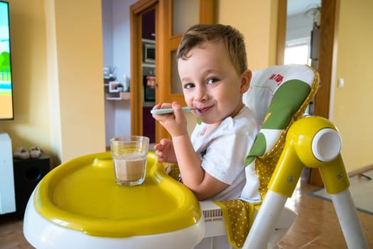 Beautiful child having breakfast with cereal and milk.